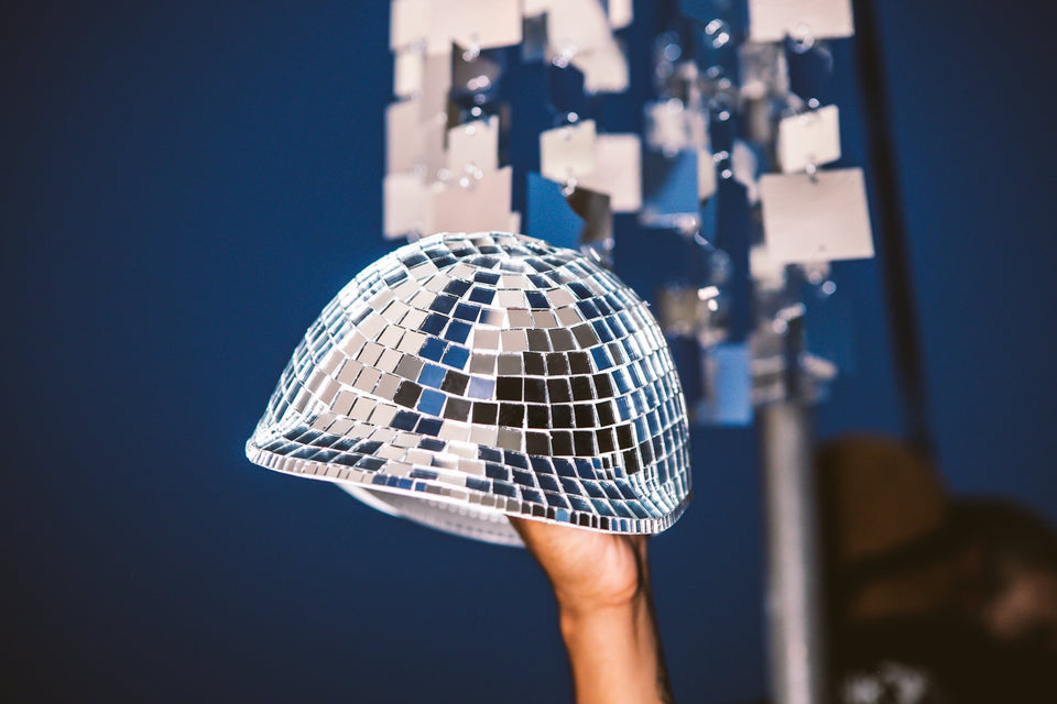 Up-close view of the Thousand Deep disco ball hat, being hoisted towards the sky. Front-facing view of the hat. Photo taken on rooftop at Lightning Society in Brooklyn, New York 