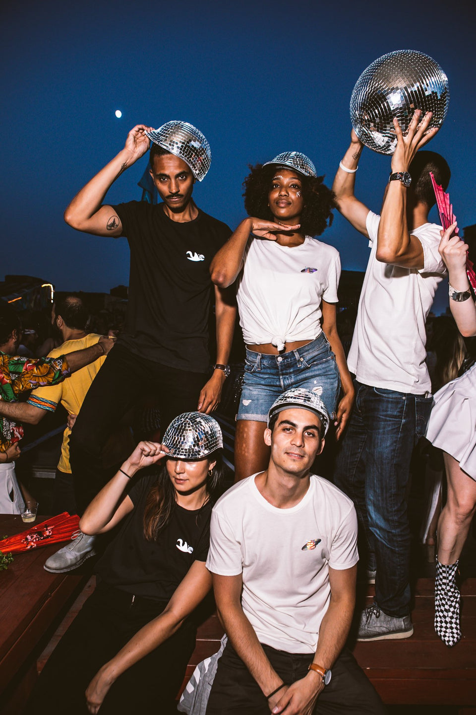 Male and female models all wearing the Thousand Deep disco hat, dancing to music with a disco ball. Photo taken on rooftop at Lightning Society in Brooklyn, New York