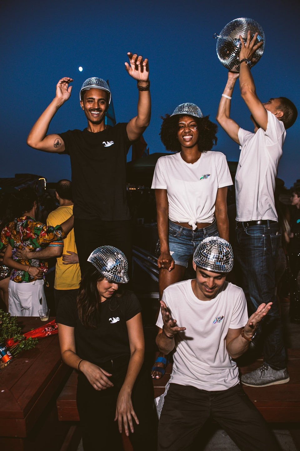 Male and female models all wearing the Thousand Deep disco hat, dancing to music with a disco ball. Photo taken on rooftop at Lightning Society in Brooklyn, New York